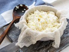 Homemade fresh cottage cheese in gauze and a bowl on the table with linen.