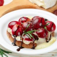 Bruschetta of Camembert or brie cheese with red grapes, rosemary and balsamic. crostini. Gourmet wine snacks for foodies. Italian antipasti. Selective focus