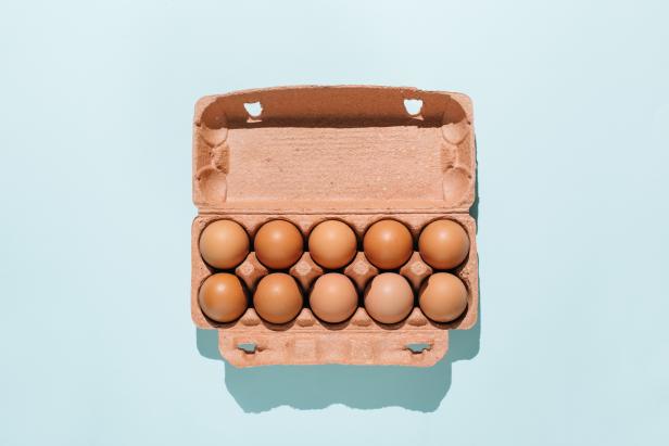 Organic eggs in cartons tray on blue background. Flat lay, top view