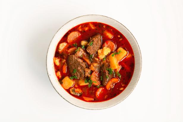 Traditional hungarian goulash soup (beef stew, potato, celery, parsley, carror, cummin, red pepper spice) on white background
