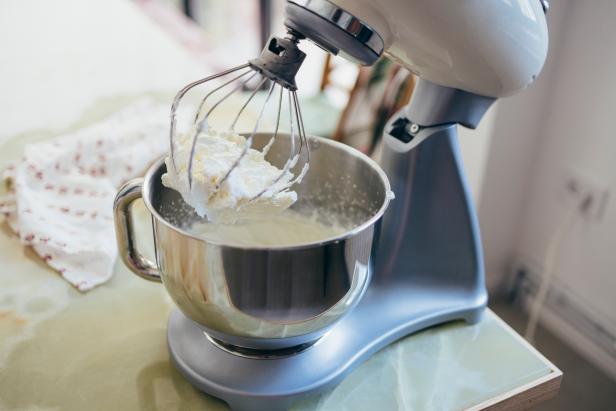 Stand mixer with whipped cream on the table in the kitchen.