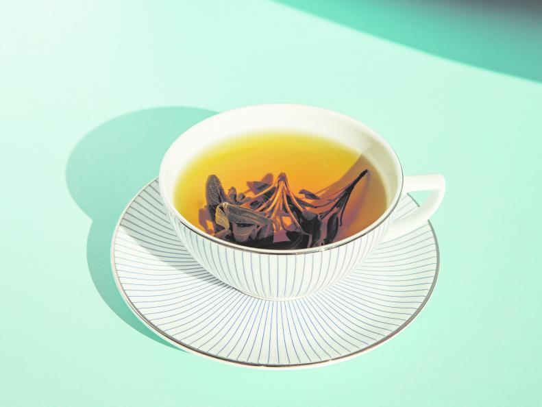 Herbal green tea in a white cup with a white saucer on color background
