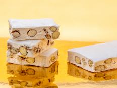 Nougat with almonds and hazelnuts on a golden background where it is reflected, copy space