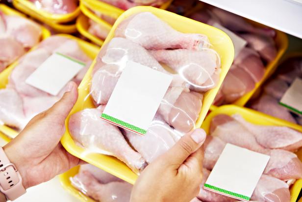 1261557308 Human hands with chicken meat in the store