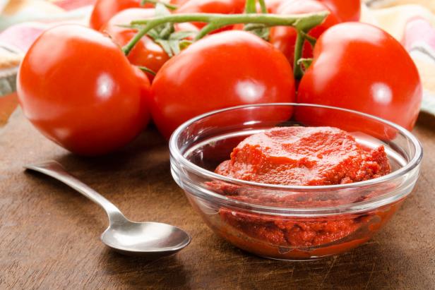 fresh tomato and paste in a glass bowl on wooden board