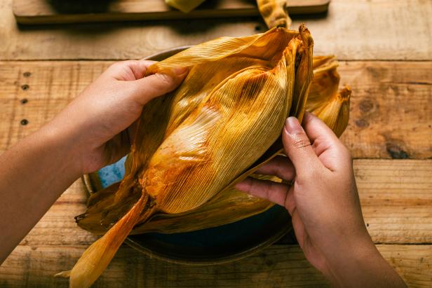 Person opening a tamale with his hands. Tamale, typical Mexican food.