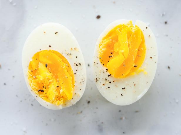 Hard boiled eggs cut in half and seasoned with salt and pepper on marble surface.