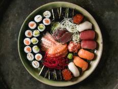 Sushi Set nigiri sashimi and sushi rolls in ceramic serving plate with salad over dark metal texture background. Flat lay, space. Japan menu