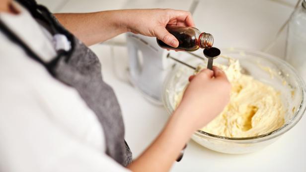 Cropped shot of an unrecognizable woman adding vanilla essence to her cake mixture