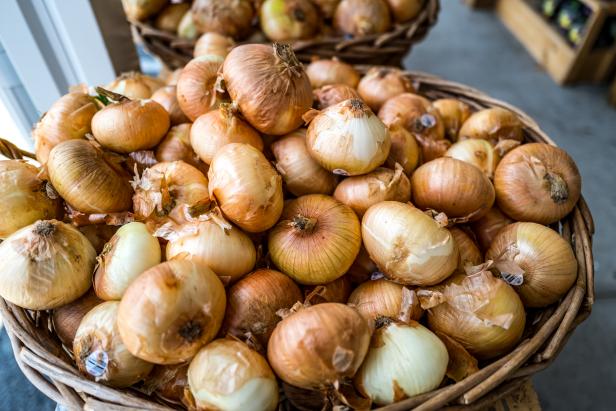 A scene from a farmstand on Cape Cod MA highlighting a full bucket of fresh Visalia onions for sale.
