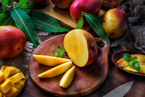 Healthy eating themes. Tropical Fruits: Sliced mangos in a clay rustic plate on a wooden table in rustic kitchen