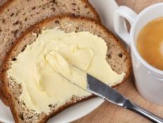 Bread and butter. A knife spreading butter on bread