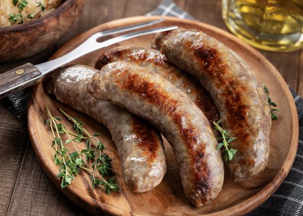 Fried bratwurst garnished with thyme on a plate on a rustic wooden table