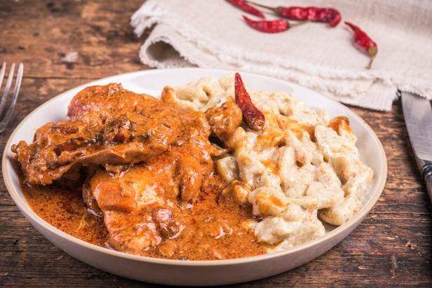 Hungarian chicken stew - chicken paprikash with dumplings, gnocchi on a plate, close-up, rustic style