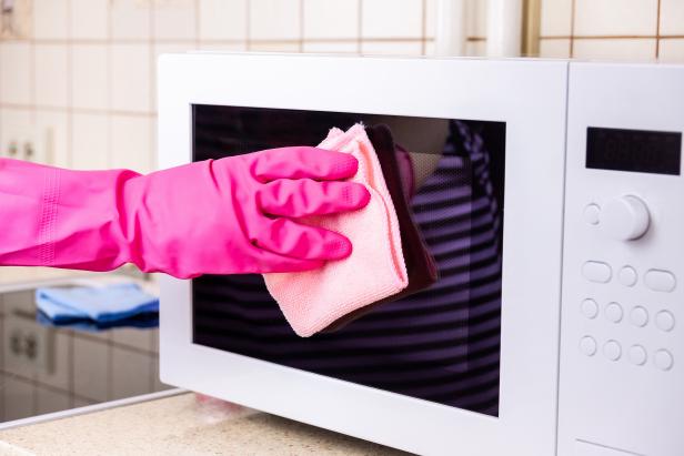 Woman's hands cleaning kitchen top in rubber protective gloves