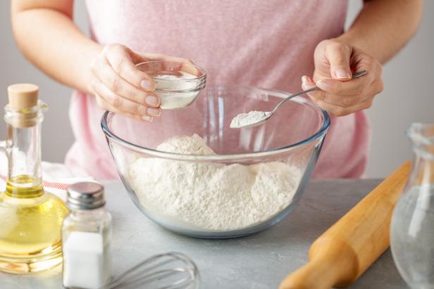 Women adds the baking powder into the glass bowl with flour. Step by step recipe of homemade mexican flatbread tortilla.