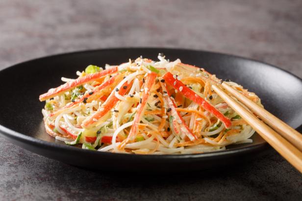 Kani salad is a Japanese style seafood salad made with crab stick closeup in the plate on the table. Horizontal