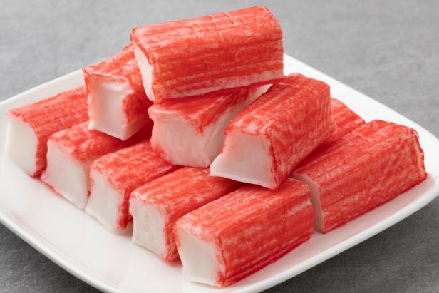 Plate with whole and half red Japanese Surimi sticks close up