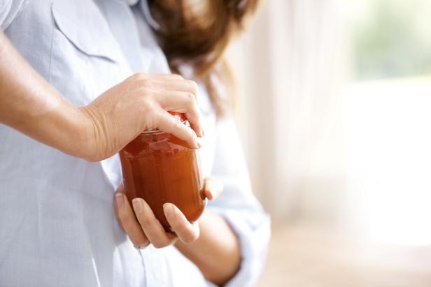 Cropped image of a woman trying to open a jar in the kitchen