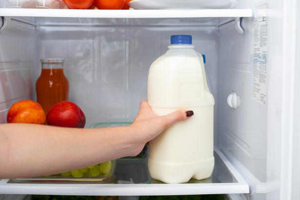 Female hand taking bottle of milk from a fridge close up