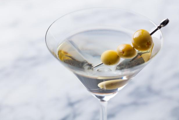 Martini cocktail with green olives on marble board. Close up