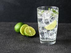 Glass of sparkling water with ice cubes and slice of lime