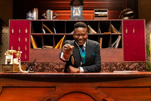 Host Tituss Burgess at the front desk, as seen on Last Bite Hotel, Season 1.