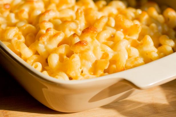 115048790 Homemade macaroni and cheese casserole sitting in the light of a window photograph. The pasta has a cheesy buttery look and shows only the partial casserole dish. Macaroni and cheese is a comfort food for many.