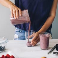 Woman pouring smoothie into glasses