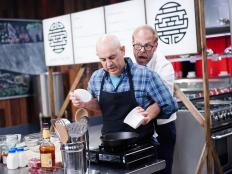 Host Alton Brown and Guest Judge Simon Majumdar perform the Round 3 sabotage element, No Hands, as seen on Food Network's Cutthroat Kitchen, Season 11.