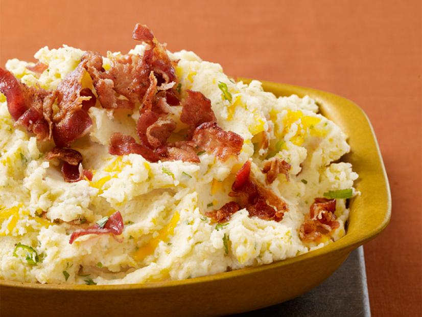A Gold Dish Filled with Mashed Potatoes that have Crumbled Bacon atop Them