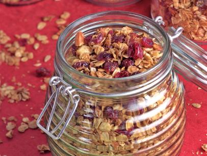 Cranberry Almond Granola Mixture in Four Glass Storage Containers Positioned on a Red and Green Table Setting