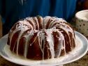 Bundt Cake with Pineapple Glaze and Sprinkled Coconut Flakes on Top a White Cake Pedestal