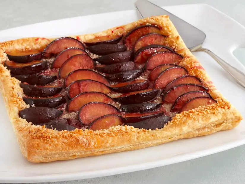 A Pastry With Four Rows of Carmelized Plums placed on a White Dish