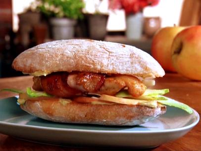 Bacon Wrapped Chicken Sandwich on A Blue Gray Plate Atop a Wooden Table