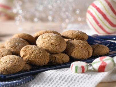 Pebble Shaped Ginger Bread Cookies on a Dark Blue Plate Surrounded by Christmas Peppermint Decorations