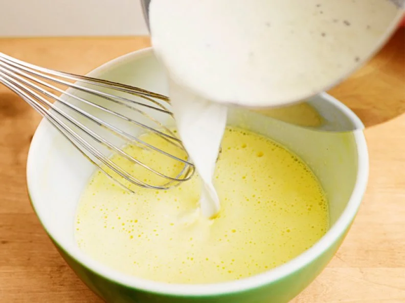 Pouring Wet Ingredients into a Mixing Bowl that contains a Whisk 