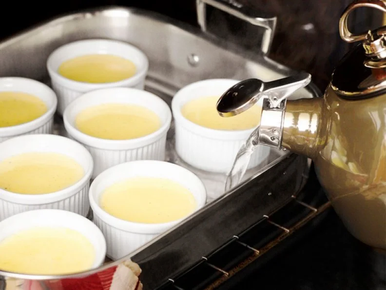 Pouring water into a cooking pan to cook creme brulee