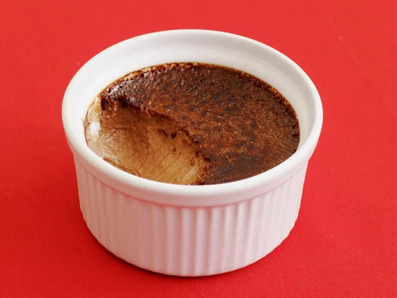 A mocha dessert in a small white dish on a red tablecloth