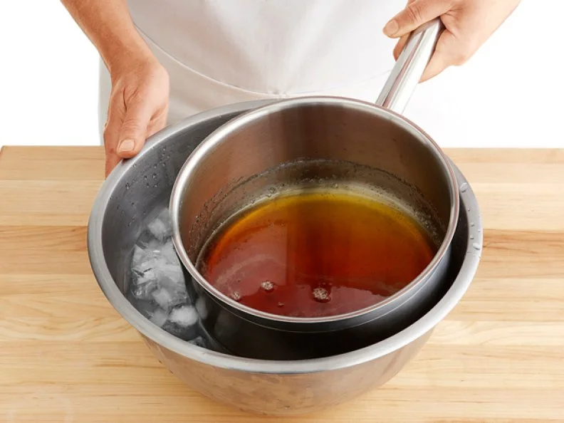 A Sauce Pan with Caramel Placed inside of a Metal Bowl Filled With Ice
