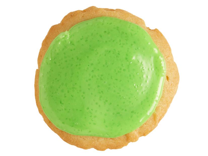 A cookie with lime frosting on top placed against a white background