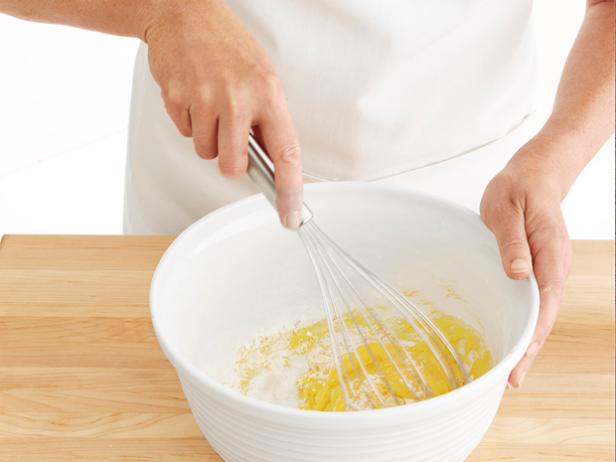 Pastry chef pouring flour into bowl to beat with blender Stock