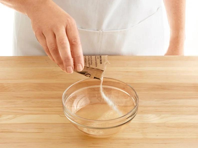 Gelatine Being Poured From a Packet into a Clear Glass Bowl