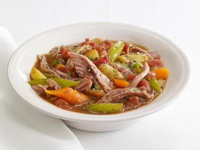 Stew made of pork, carrots, celery and other vegetables in a white bowl on a white table setting