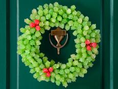 A holiday wreath made of green and red rock candy hung on a green door