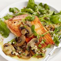 Arctic fish on a plate with greens and mushrooms on a plain white plate