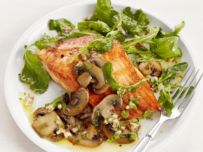 Arctic fish on a plate with greens and mushrooms on a plain white plate