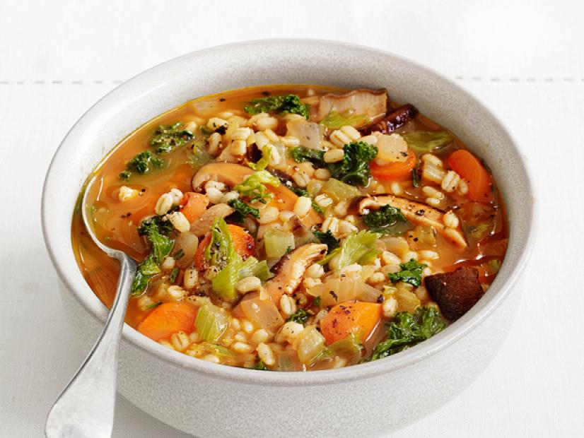 Barley stew with carrots, mushrooms, onions and greens in a gray bowl