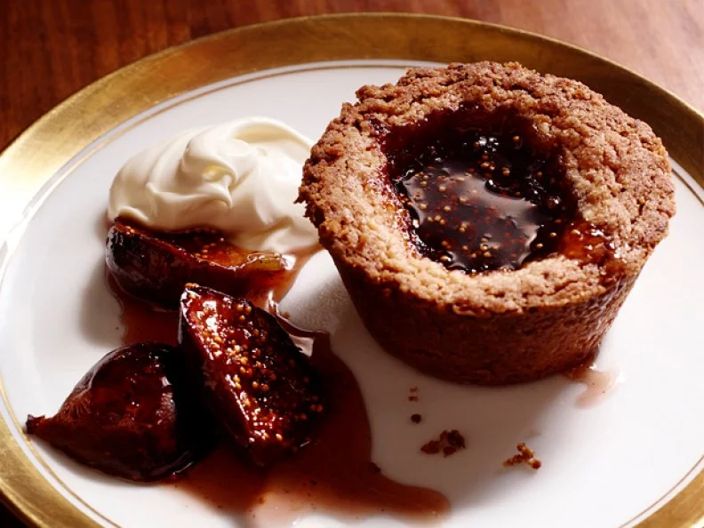 Dessert with a fruit filling next to a side of cream on a gold and white plate