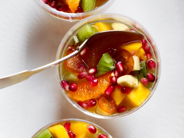 A clear bowl with a sideways spoon containing a fruit dessert